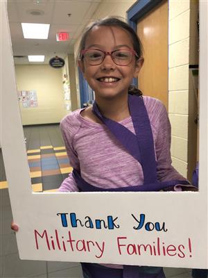 student in framed sign thanking military families 